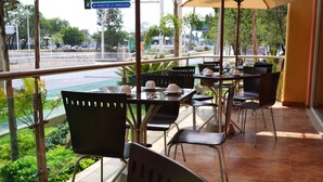 A restaurant with outdoor seating, tables, chairs, and a view of the street. - Hostalia Hotel Expo & Business Class (Guadalajara)