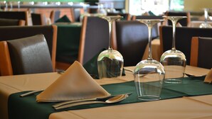 A restaurant setting with tables set for dining, featuring clear glassware and neatly arranged napkins. - Hostalia Hotel Expo & Business Class (Guadalajara)