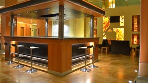 A modern bar area with a wooden counter, metal stools, and a glass railing. - Hostalia Hotel Expo & Business Class (Guadalajara)