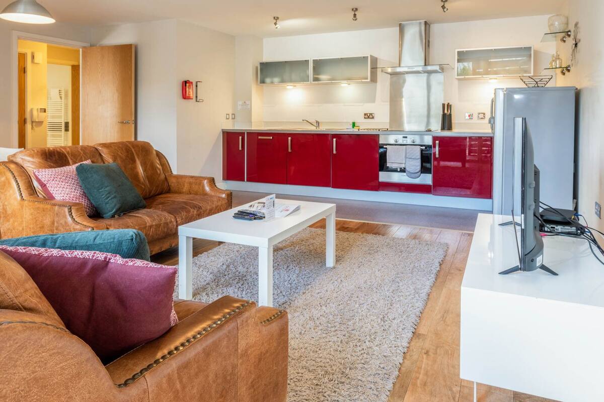 A modern living room with a leather sofa, a white coffee table, and a television.