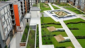 Un complexe résidentiel moderne doté d’une cour intérieure où l’on trouve un aménagement paysager aux formes géométriques et un élément décoratif aquatique.