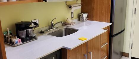 A compact kitchen with a built-in microwave, a sink, and a stainless steel refrigerator.