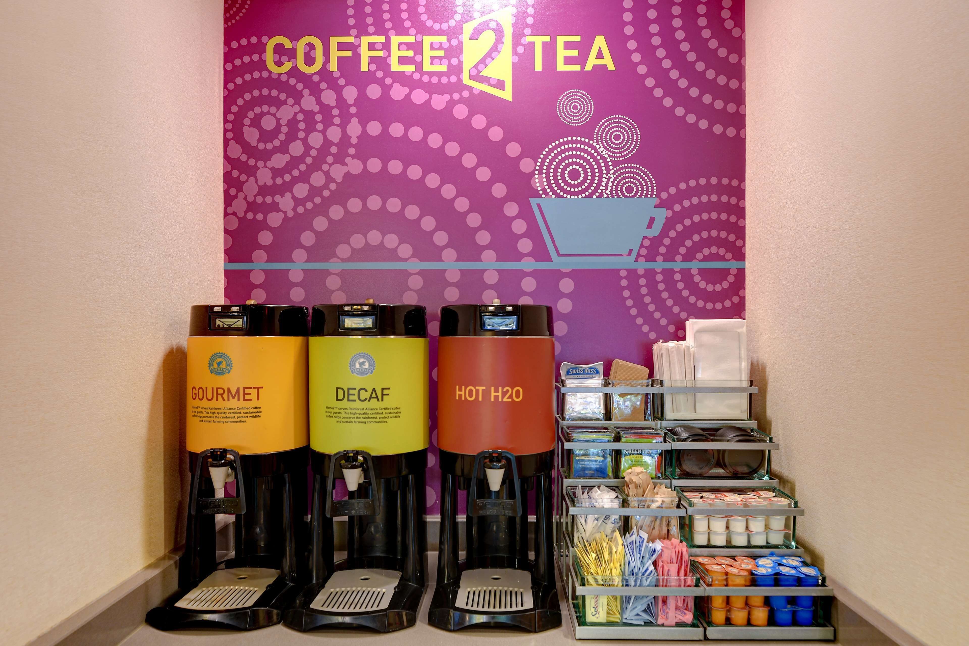 A coffee and tea station with three dispensers labeled 'Gourmet', 'Decaf', and 'Hot H2O'.