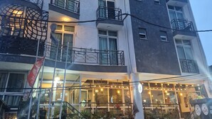 A multi-story building with balconies, a cafe on the ground floor, and outdoor lighting. - Ag Palace Hotel (Addis Ababa)