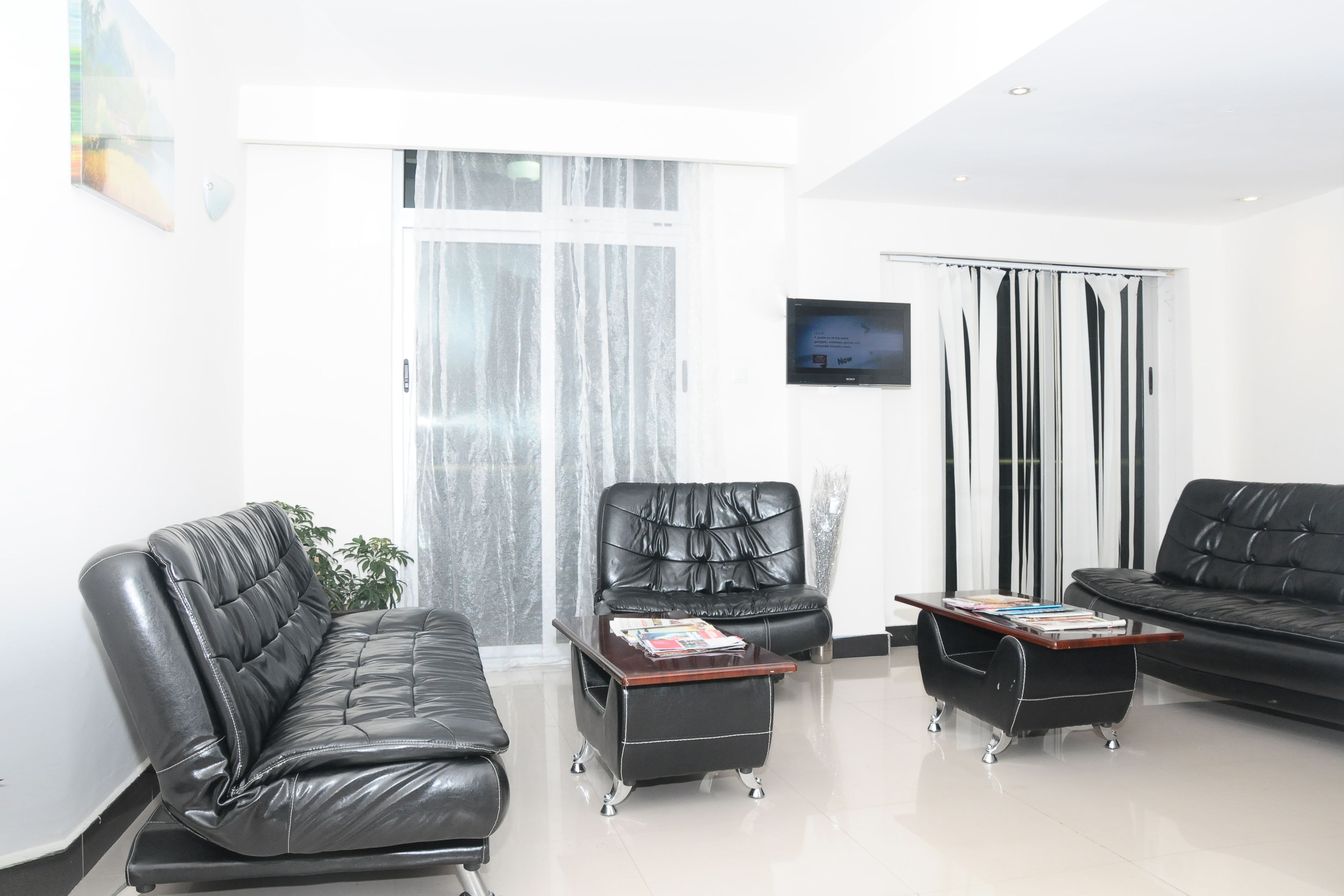 Una sala de estar moderna con un sofá de cuero negro, un sillón de cuero y una mesa de centro con revistas.