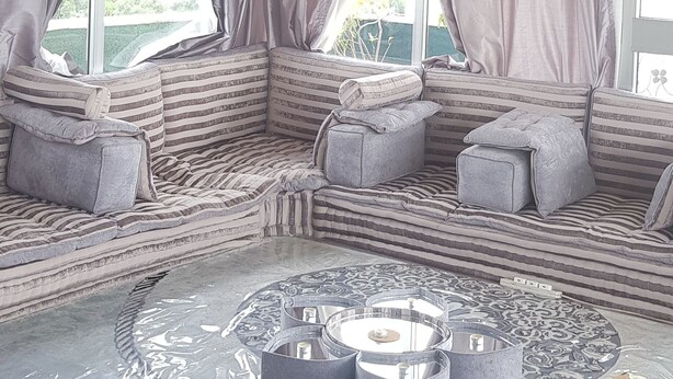 A room with a large sectional sofa, a chandelier, and a patterned rug. - Ag Palace Hotel (Addis Ababa)