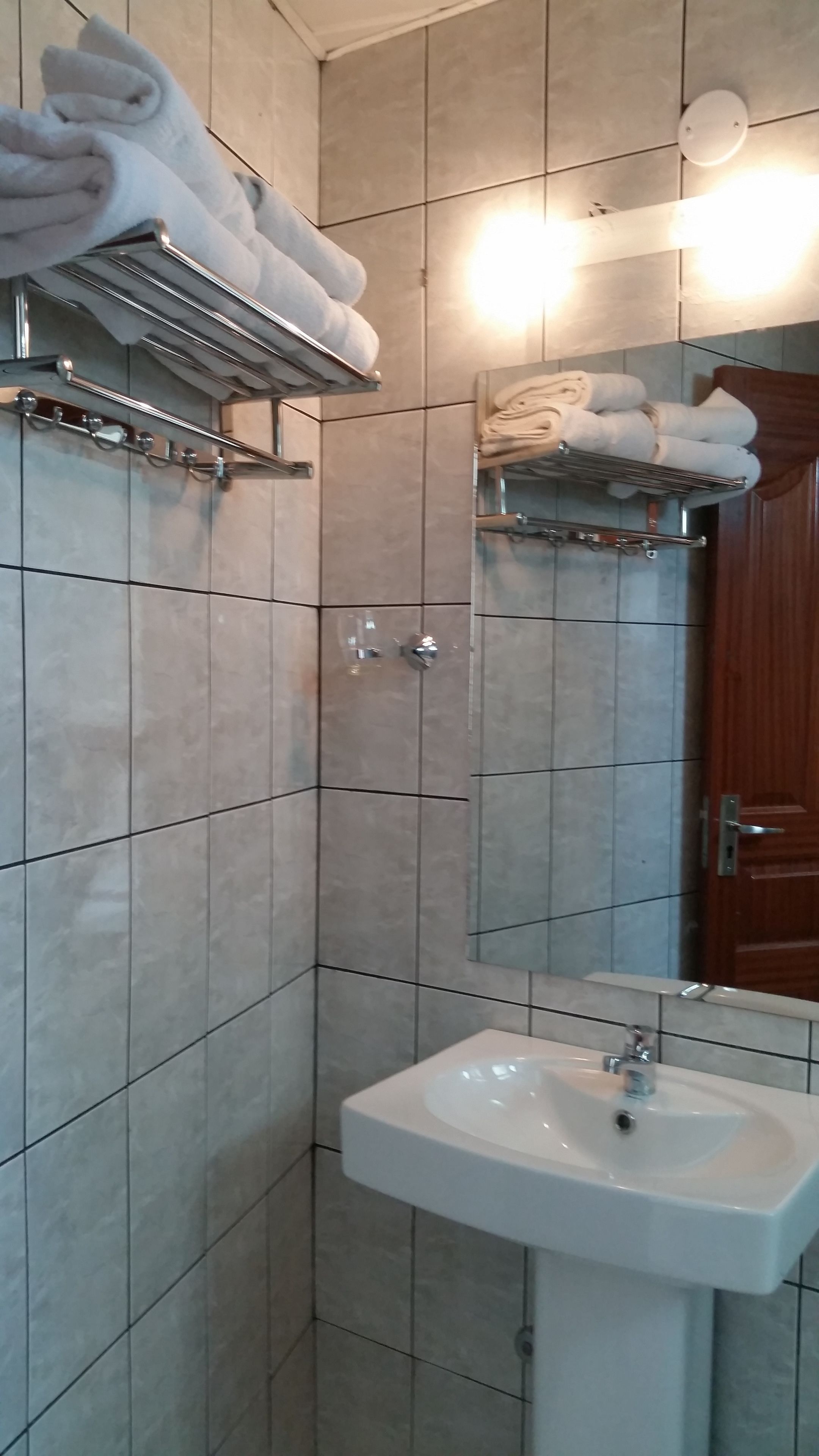 Un baño con lavamanos, toalleros y espejo.