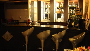A bar area with modern bar stools, a well-lit interior, and a variety of bottles on shelves. - Ag Palace Hotel (Addis Ababa)