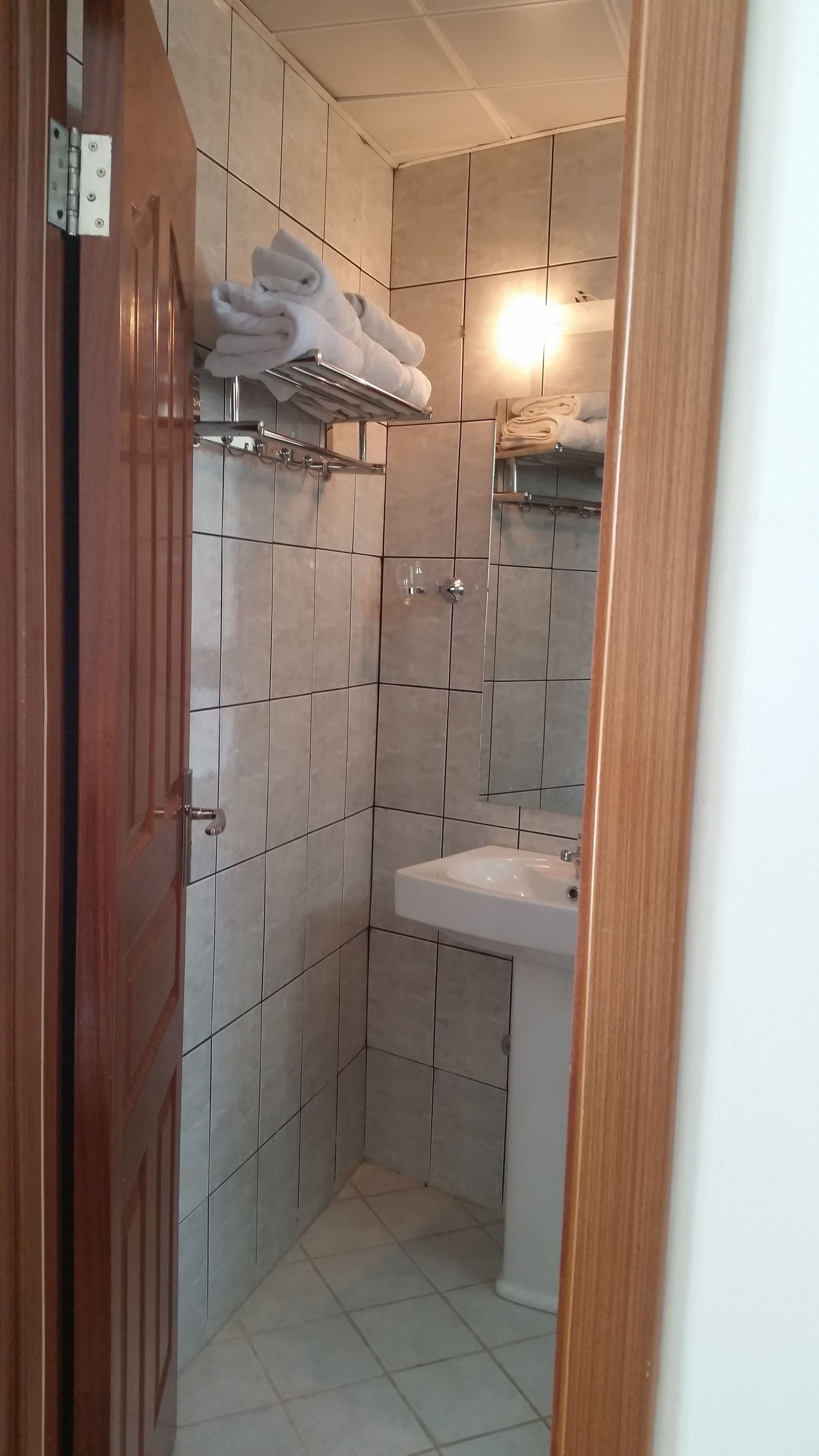 A small bathroom with tiled walls, a sink, and a towel rack.