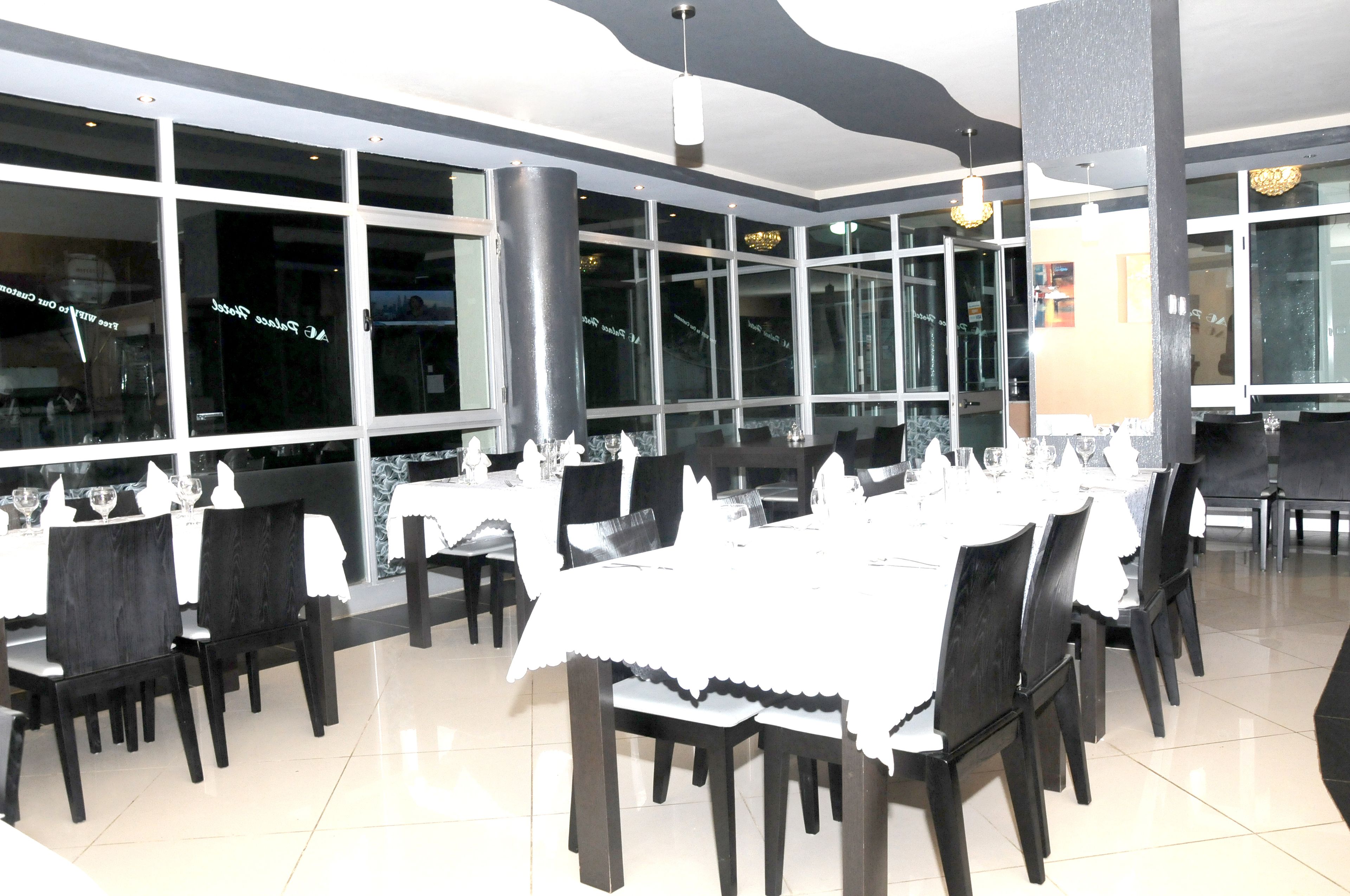 Un restaurante con varias mesas dispuestas para comer, amplios ventanales y diseño de interiores moderno.