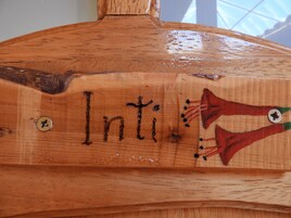 Un objeto de madera con la palabra "Inti" y un diseño rojo y verde.