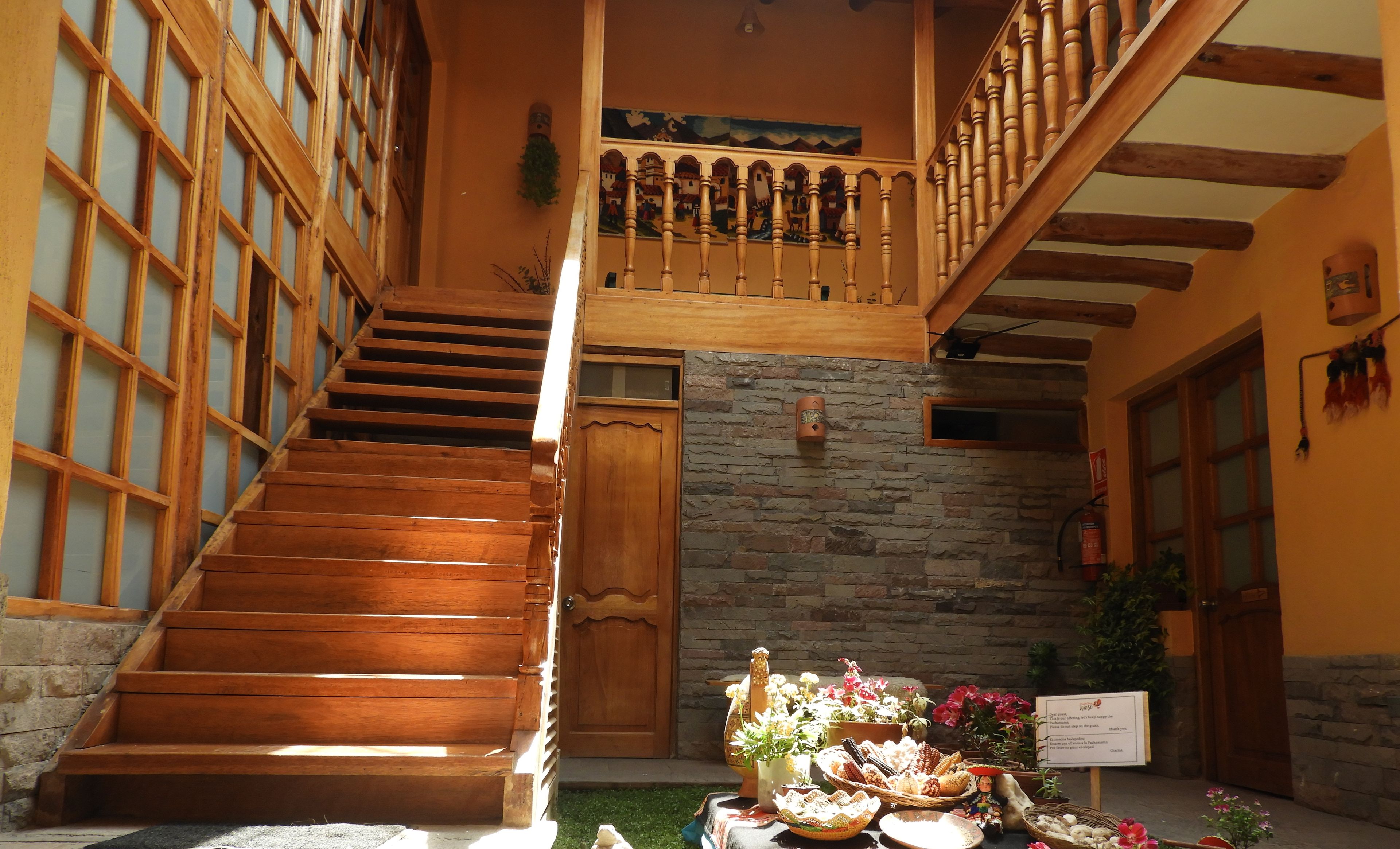 Una escalera de madera que lleva a un balcón con un muro de piedra y un letrero.