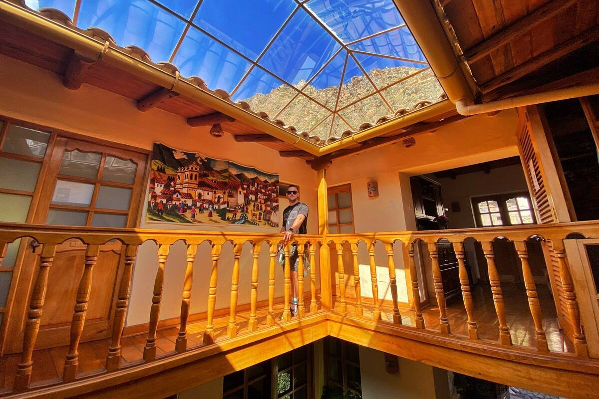 A room with a wooden balcony, a large glass skylight, and a mural on the wall.