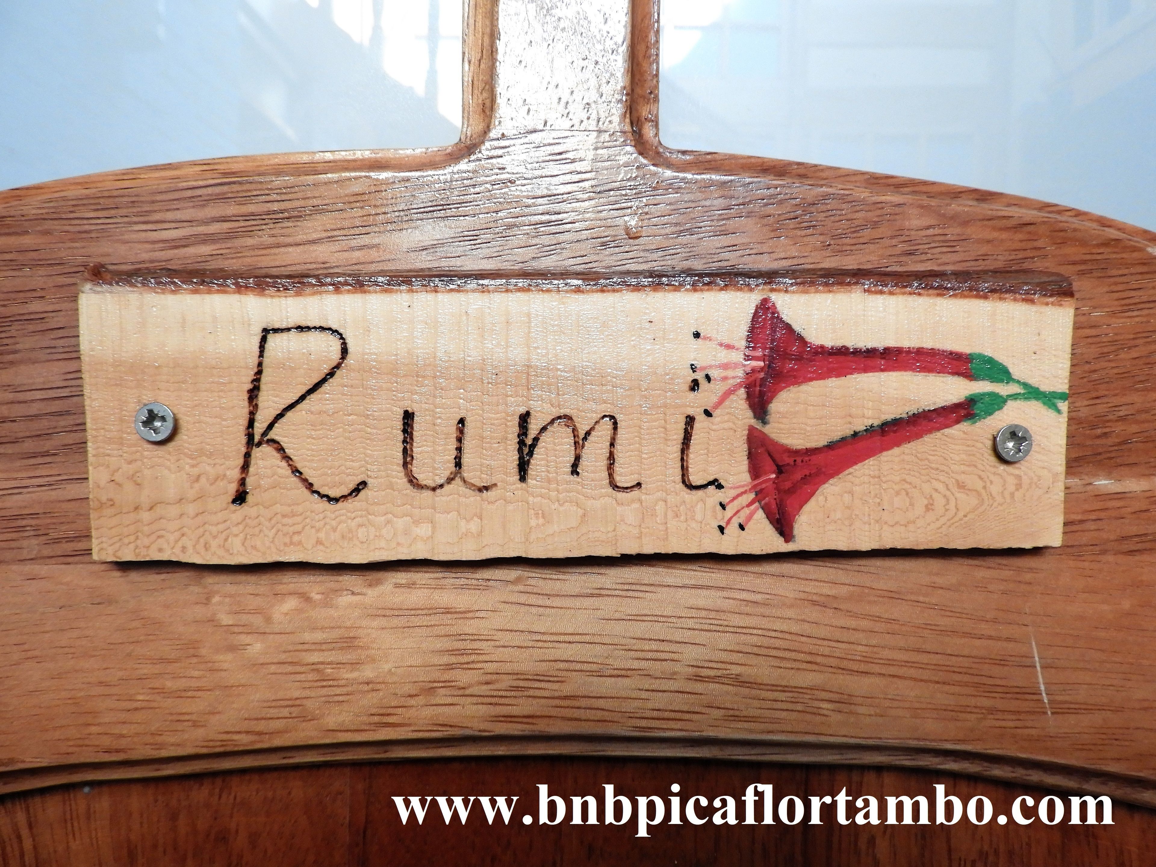 A wooden nameplate with the name "Rumi" and a red chili pepper illustration.