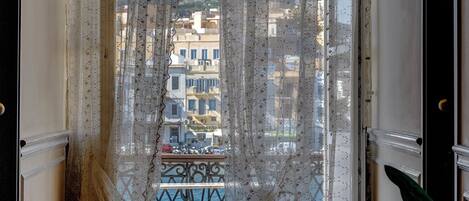Une chambre avec vue sur un balcon et un immeuble situé de l’autre côté de la rue.