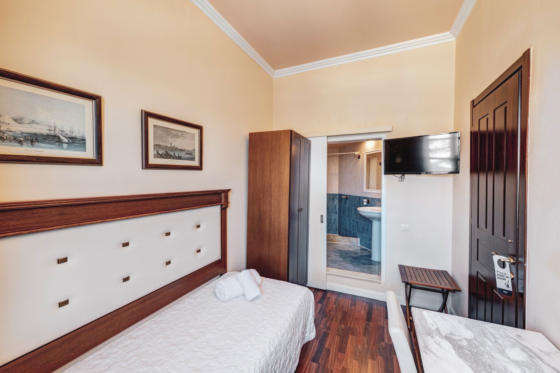 A hotel room with a bed, a television, a door, and a bathroom visible through an open door.