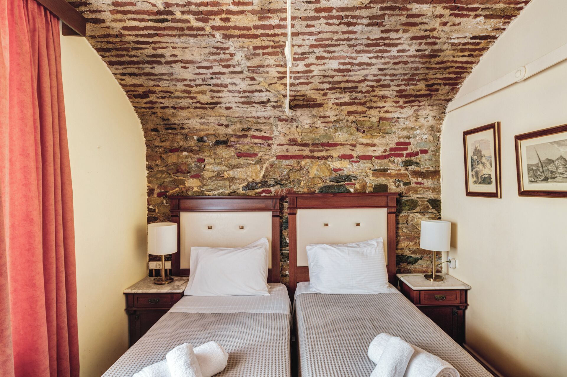A room with two beds, a stone wall, and a framed picture on the wall.