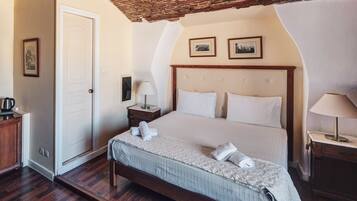 Una habitación de hotel con cama, mesita de noche, lámpara, puerta y un cuadro en la pared.