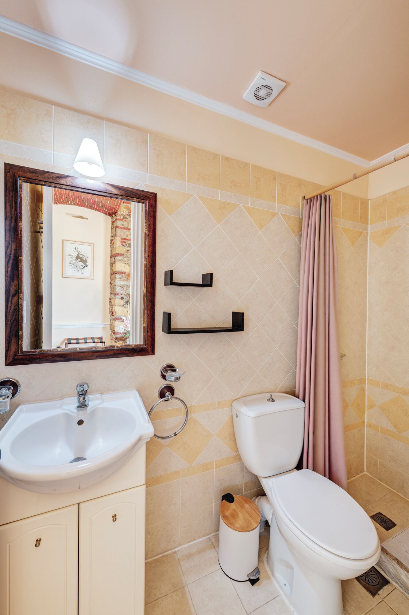 Une salle de bain équipée d’un lavabo, de toilettes, d’un miroir et d’un rideau de douche.
