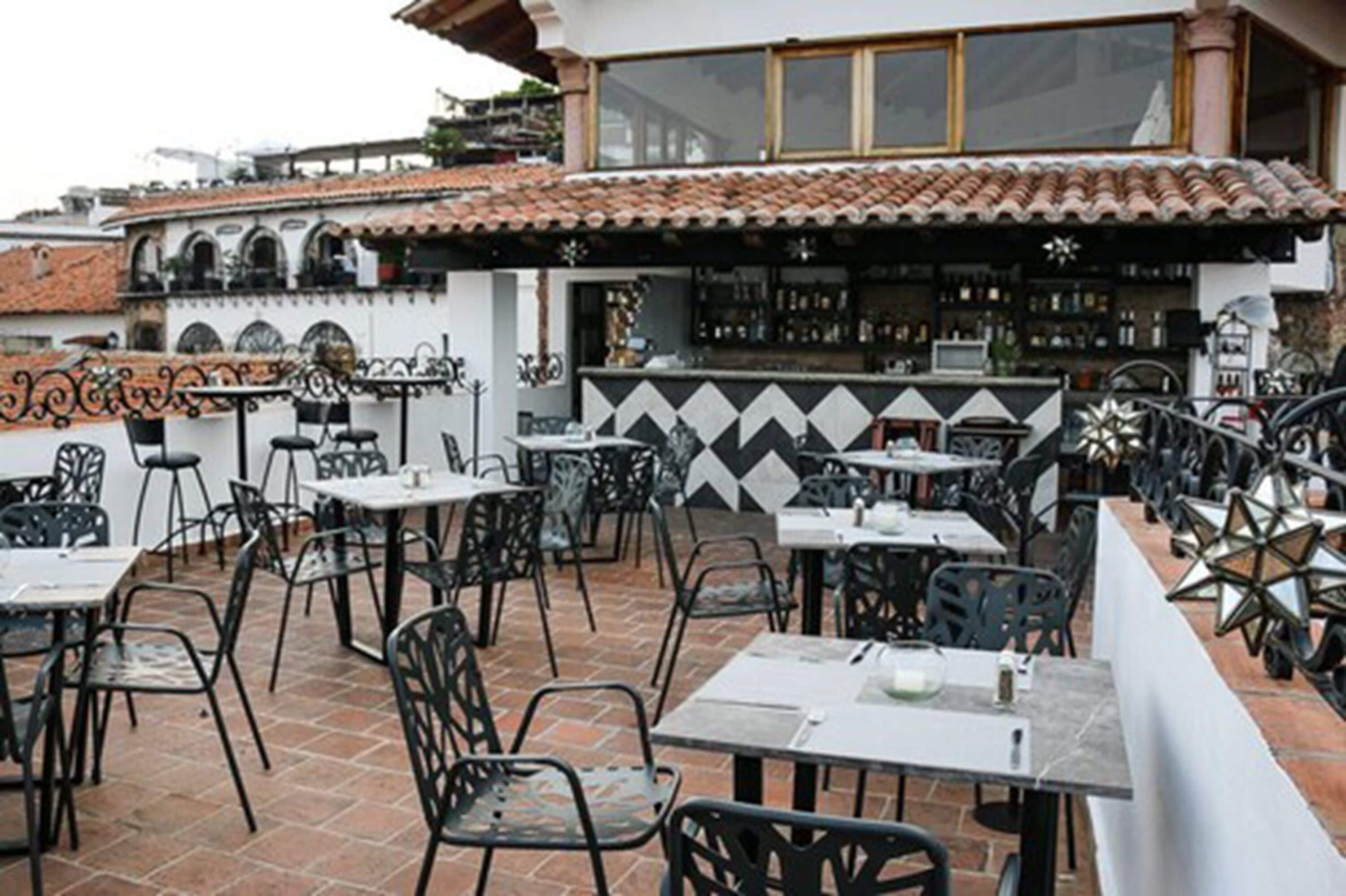 An outdoor patio with tables and chairs, a bar area, and a tiled roof.