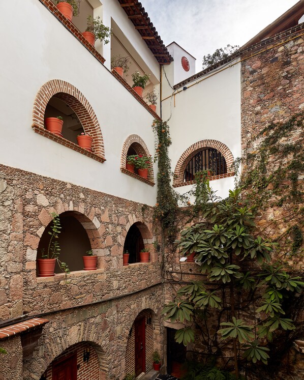 Un patio con varios arcos, plantas en macetas y una pared de piedra.