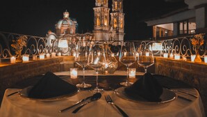 Mesa para dos con copas de vino y velas, con vista a un edificio histórico de noche.