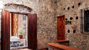 Un edificio de piedra con una puerta de madera que indica “SPA” y una planta en maceta cerca de la entrada.