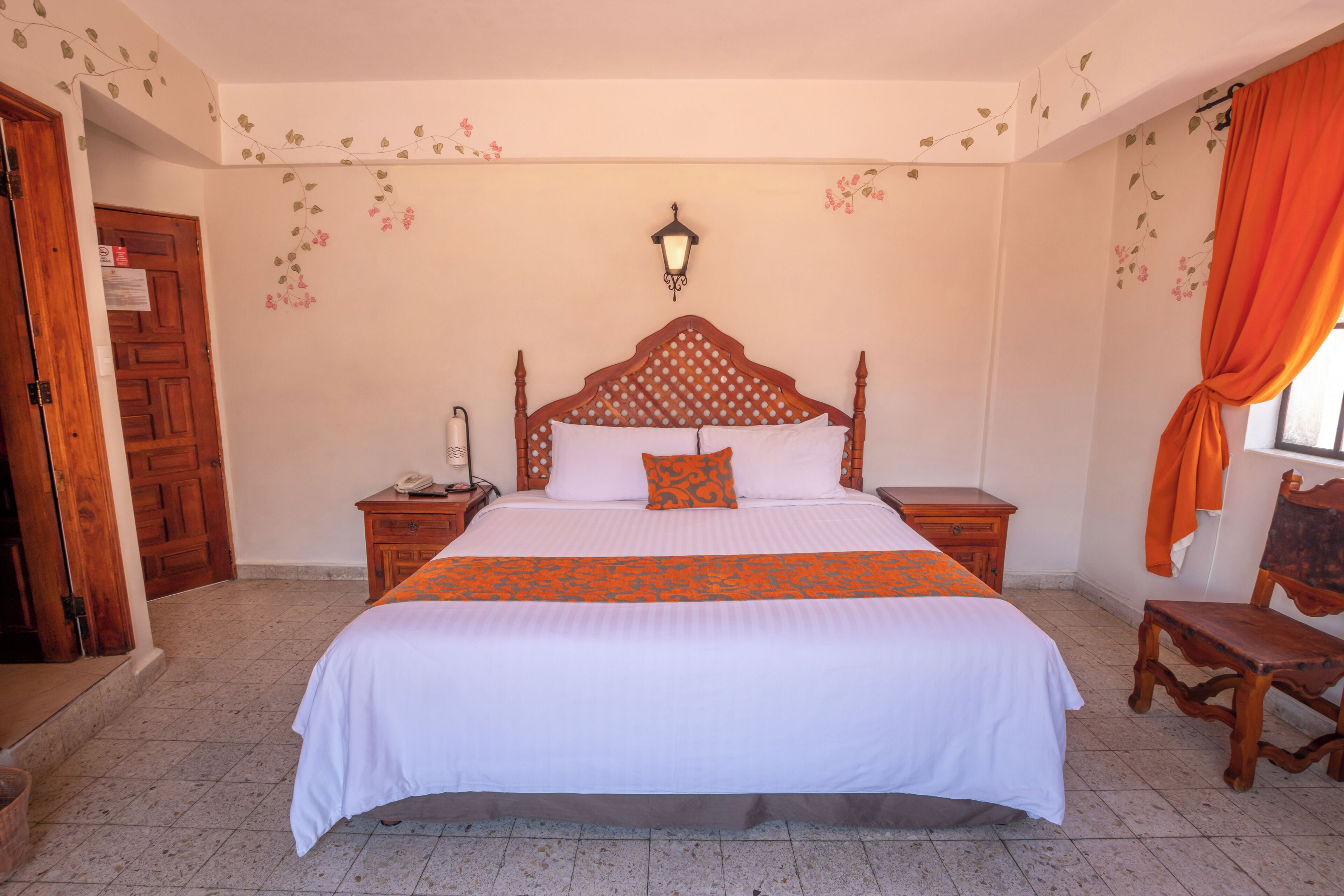 Une chambre à coucher avec un grand lit, une tête de lit en bois, des tables de chevet, une lampe et une chaise.