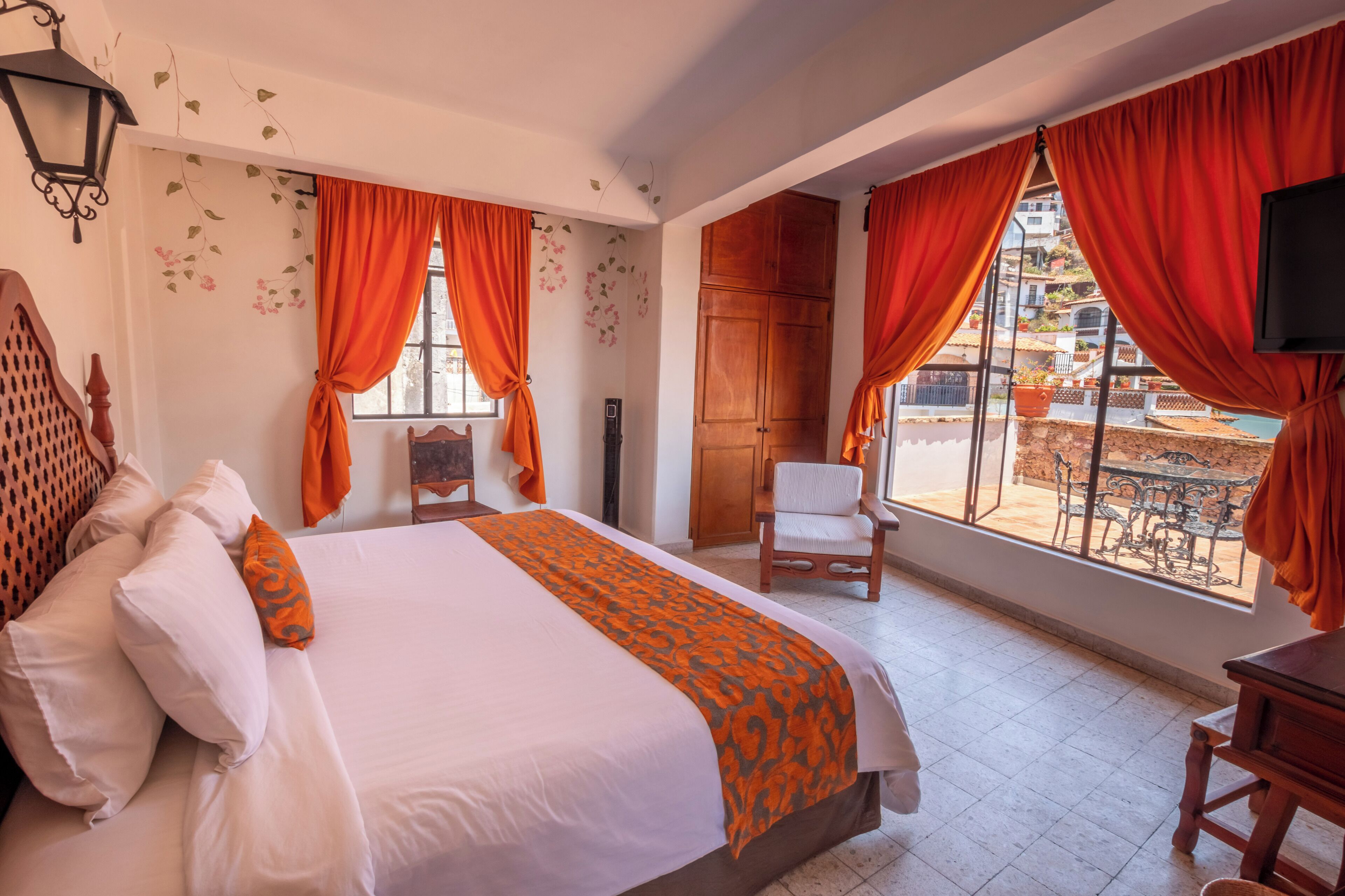 Quarto de hotel com cama, cadeira, televisão e vista para o exterior.
