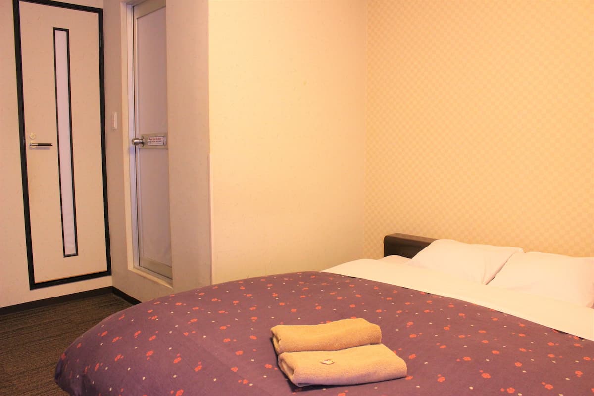 Una habitación de hotel con cama, puerta y ventana.