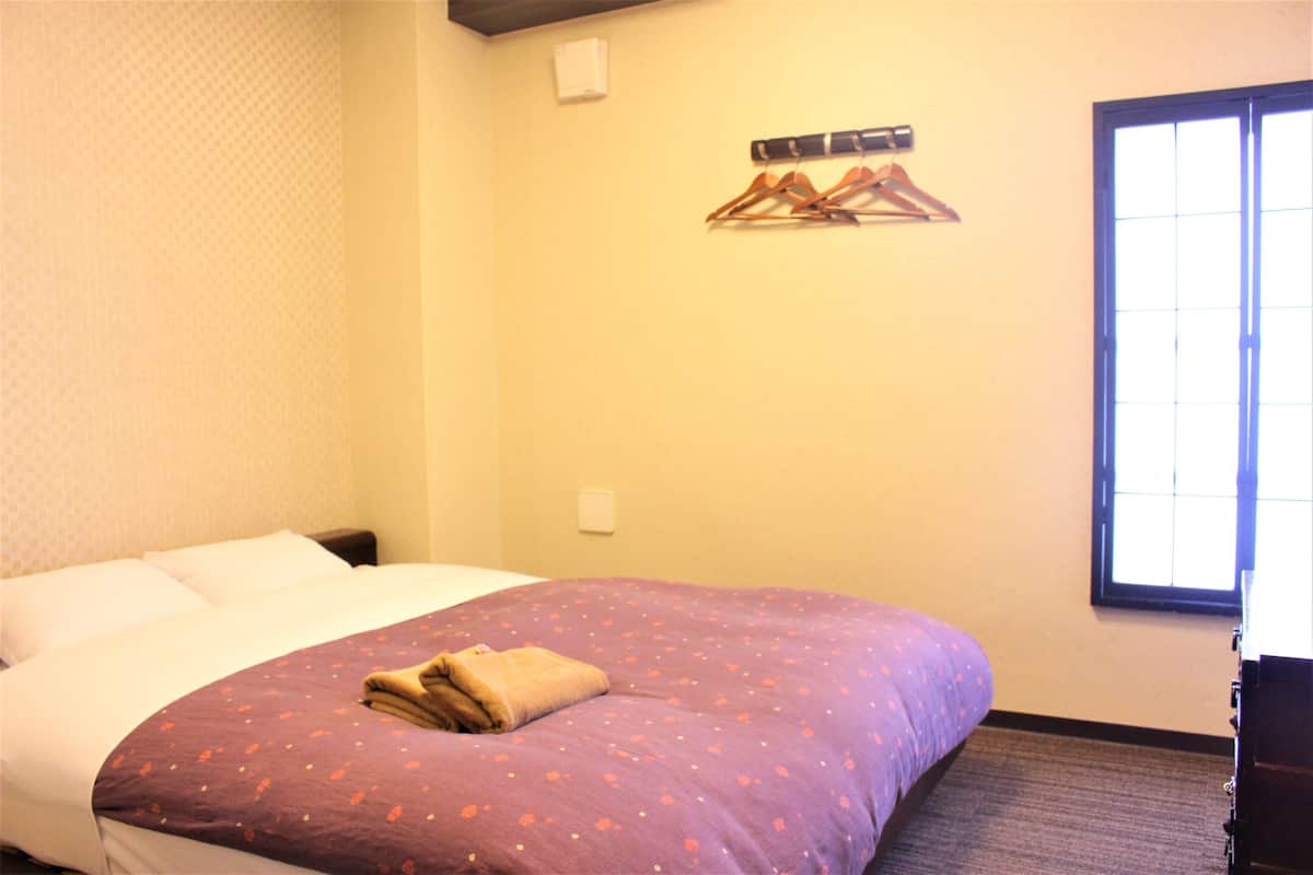 Una habitación de hotel con una cama, un ventanal y un perchero en la pared.