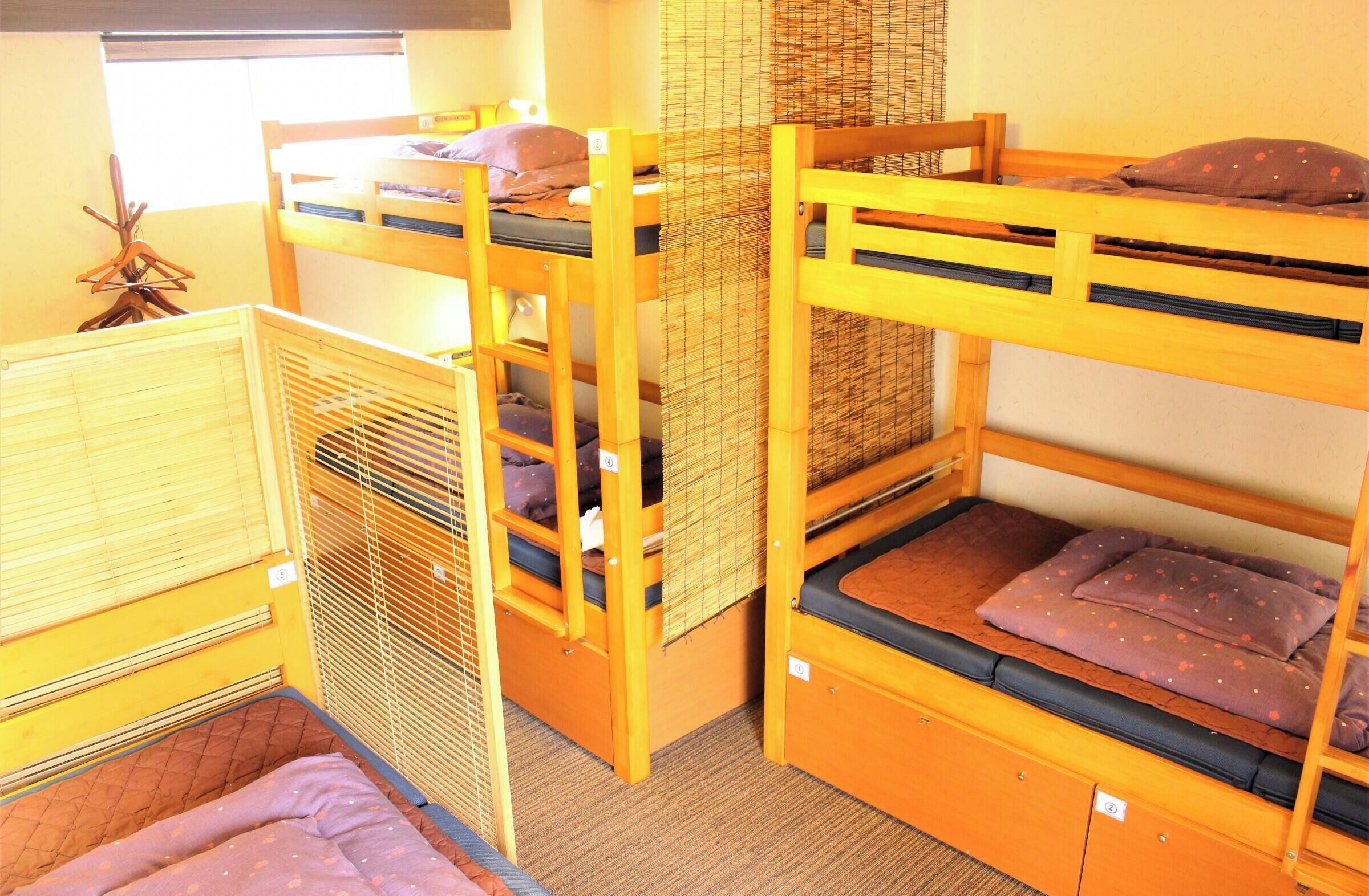A bunk bed room with a window, a small table, and a chair.