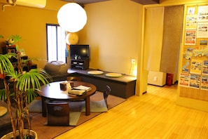 A traditional Japanese-style living room with tatami flooring, a low table, and a television.