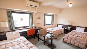A hotel room with two beds, a desk, a chair, a small table, and a calendar on the wall. - YMCA Asia Youth Center (Tokyo)