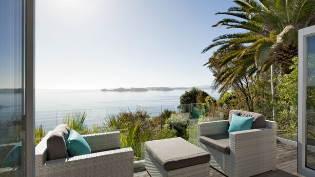 A balcony with wicker furniture, a glass railing, and a view of the sea. - Cloud 9 Luxury Villa (Russell)