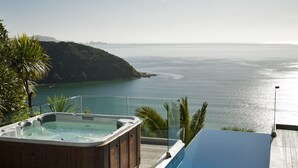 A hot tub and infinity pool overlooking a coastal view with a mountainous backdrop. - Cloud 9 Luxury Villa (Russell)