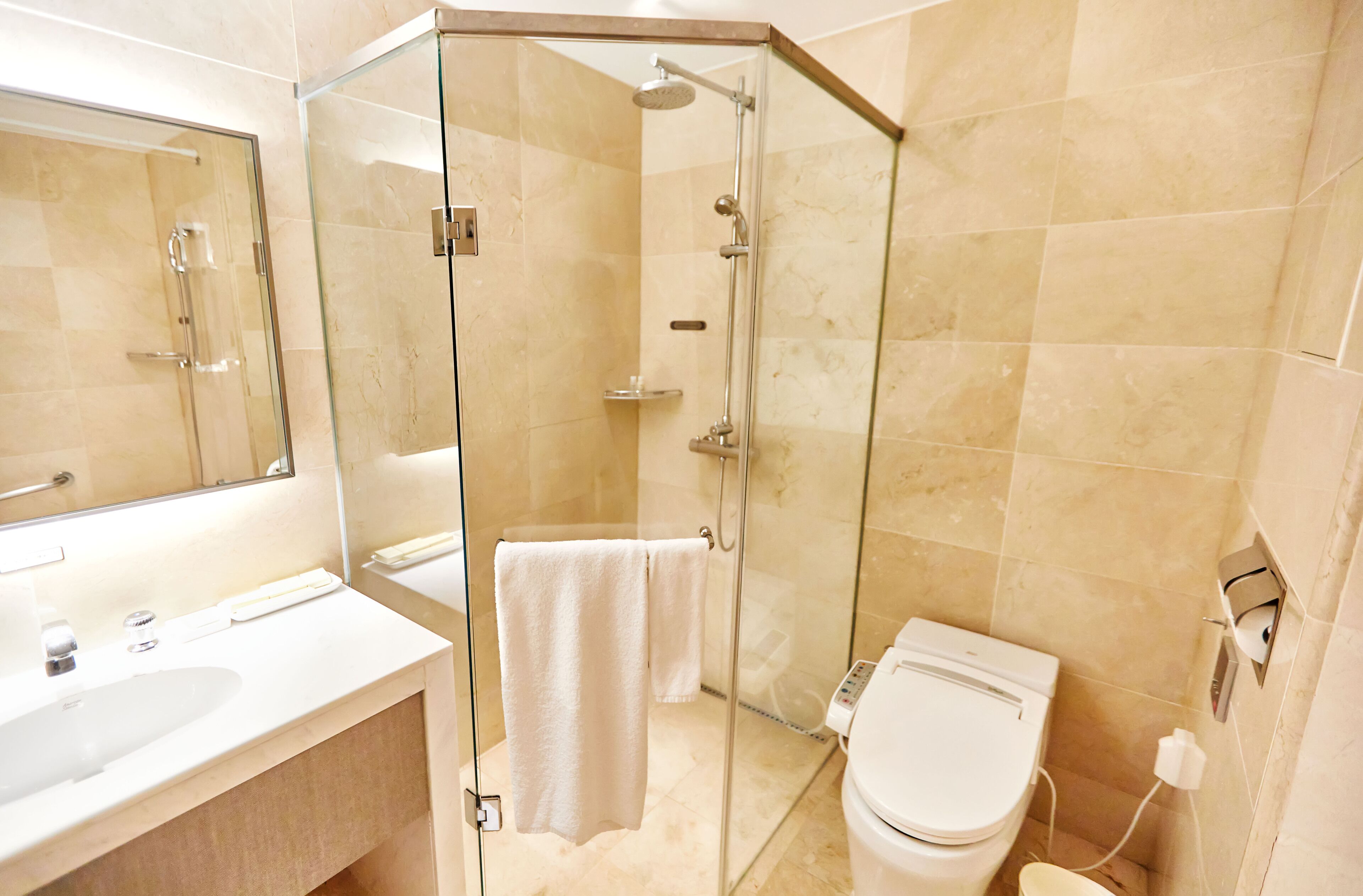 A modern bathroom with a glass-enclosed shower, a white sink, and a toilet.