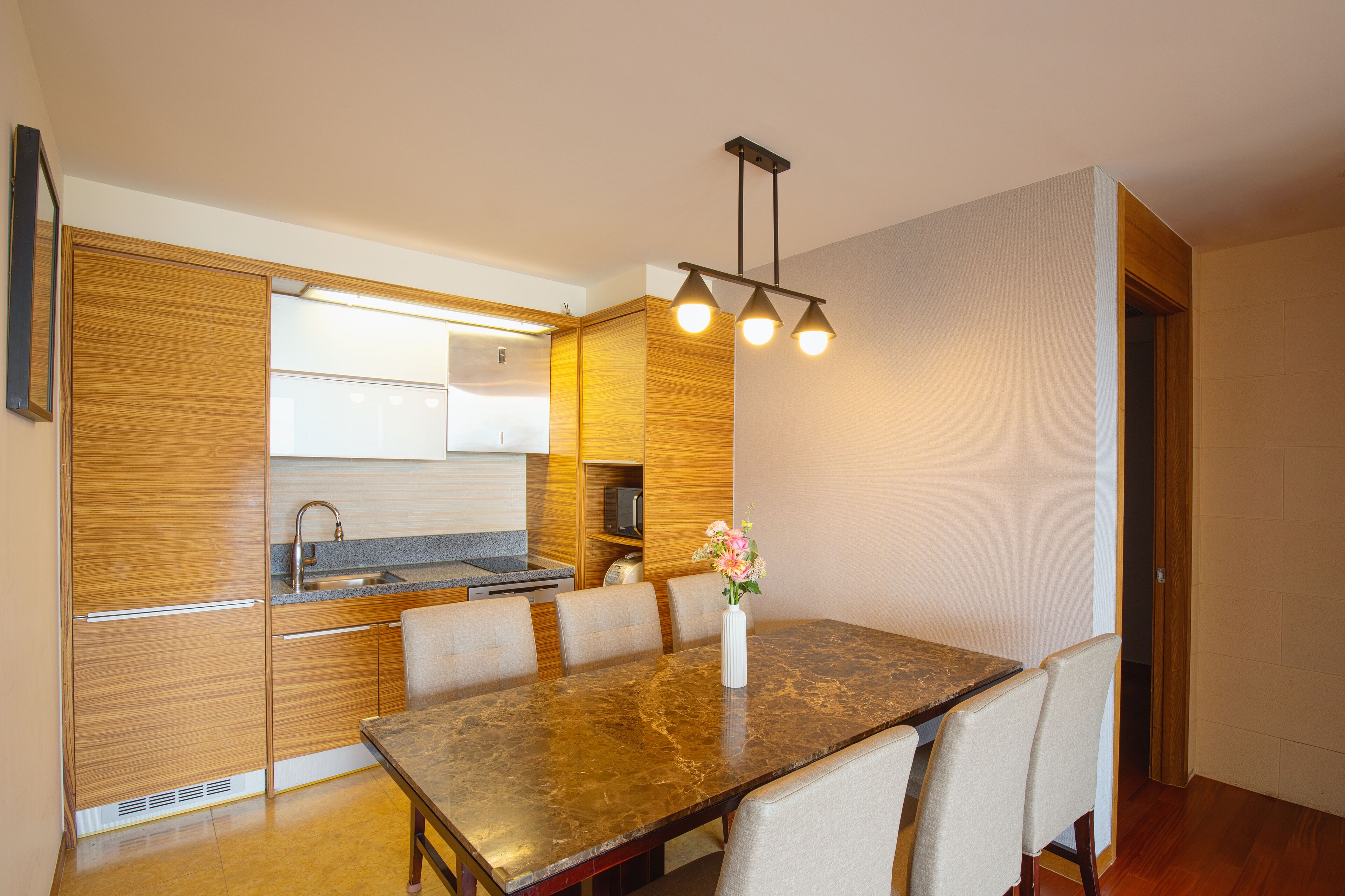 Una cocina moderna con armarios de madera, encimera de granito y comedor con mesa y sillas de mármol.