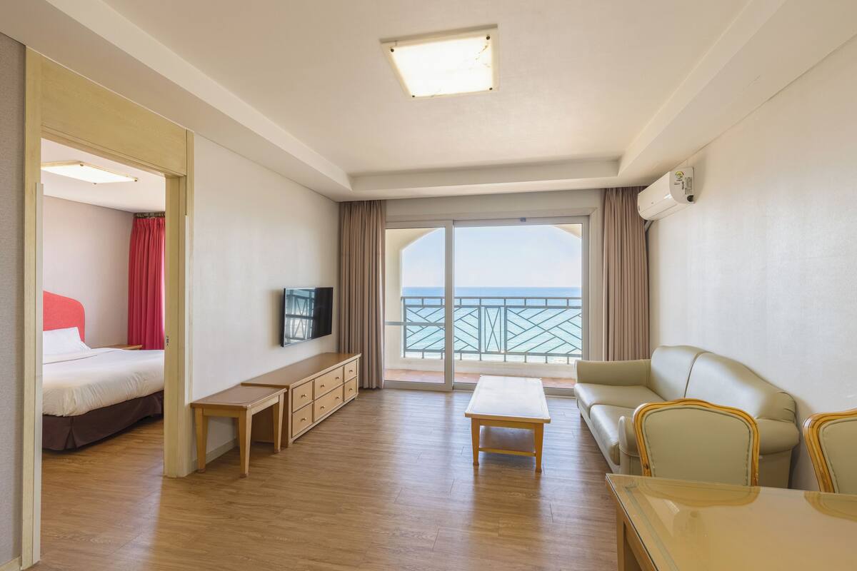 Ett hotellrum med en säng, en TV, en soffa, ett bord och en balkong med utsikt.