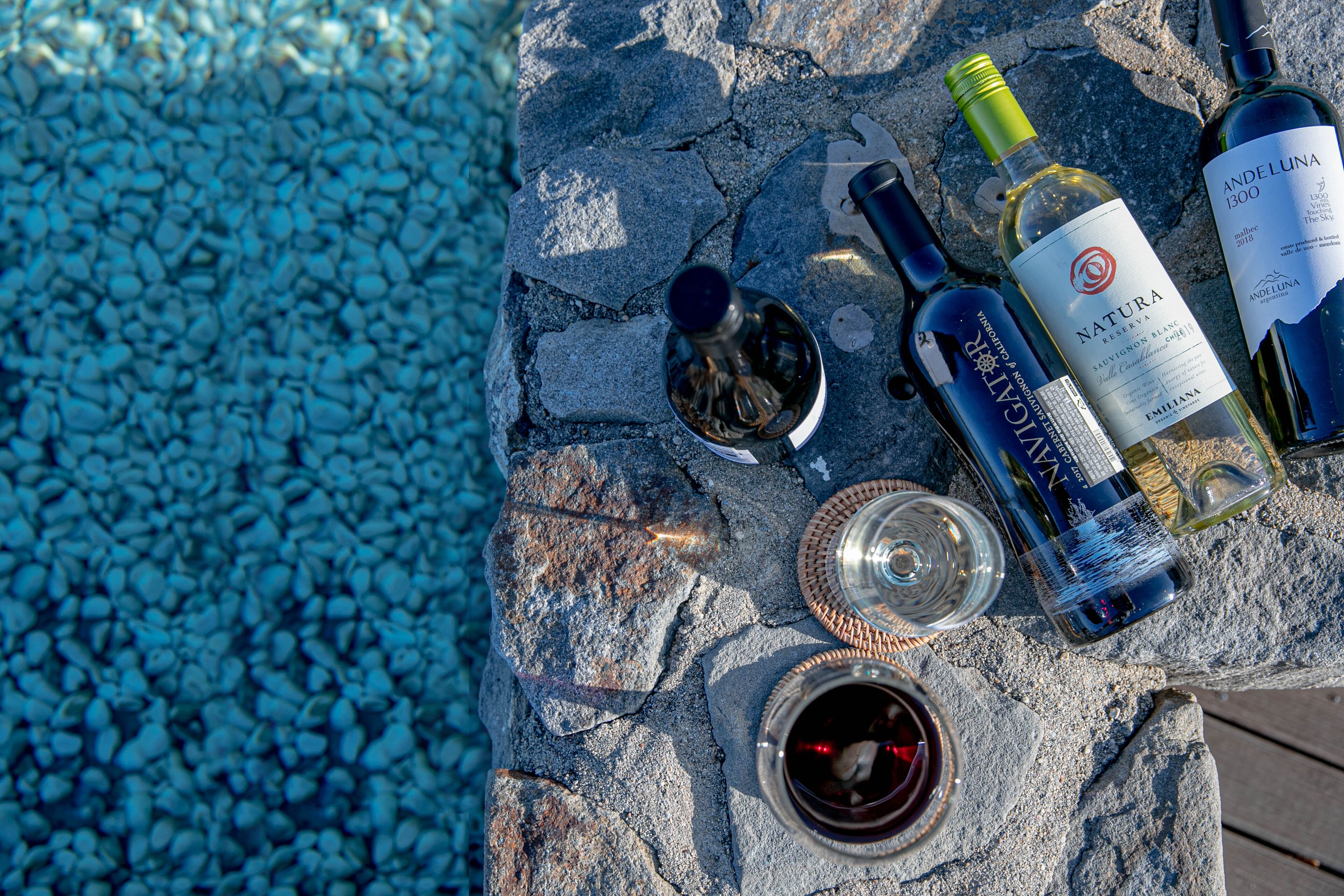 A stone table with wine bottles, glasses, and a bottle opener.