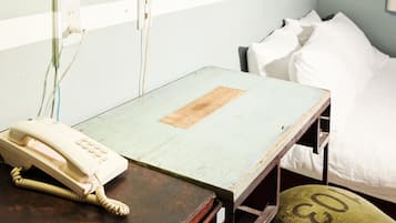 A hospital room with a bed, a bedside table with a telephone, and a pillow with a number.