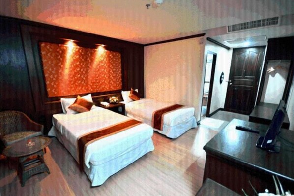 A hotel room with two beds, a desk, a chair, and a wardrobe.