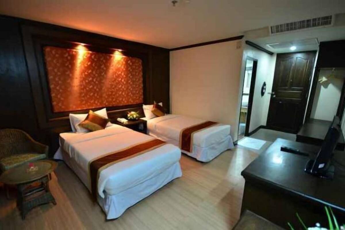 Une chambre d’hôtel avec deux lits, un bureau, une chaise et une grande fenêtre avec des rideaux.