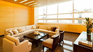 A modern living room with a sectional sofa, a coffee table, and a dining area with chairs and a small table.