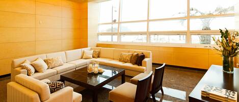 A modern living room with a sectional sofa, a coffee table, and a dining area with chairs and a small table.
