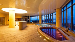 A spacious indoor pool area with a view of the mountains, surrounded by large windows and a high ceiling. - Sono Calm Yeosu (Yeosu)