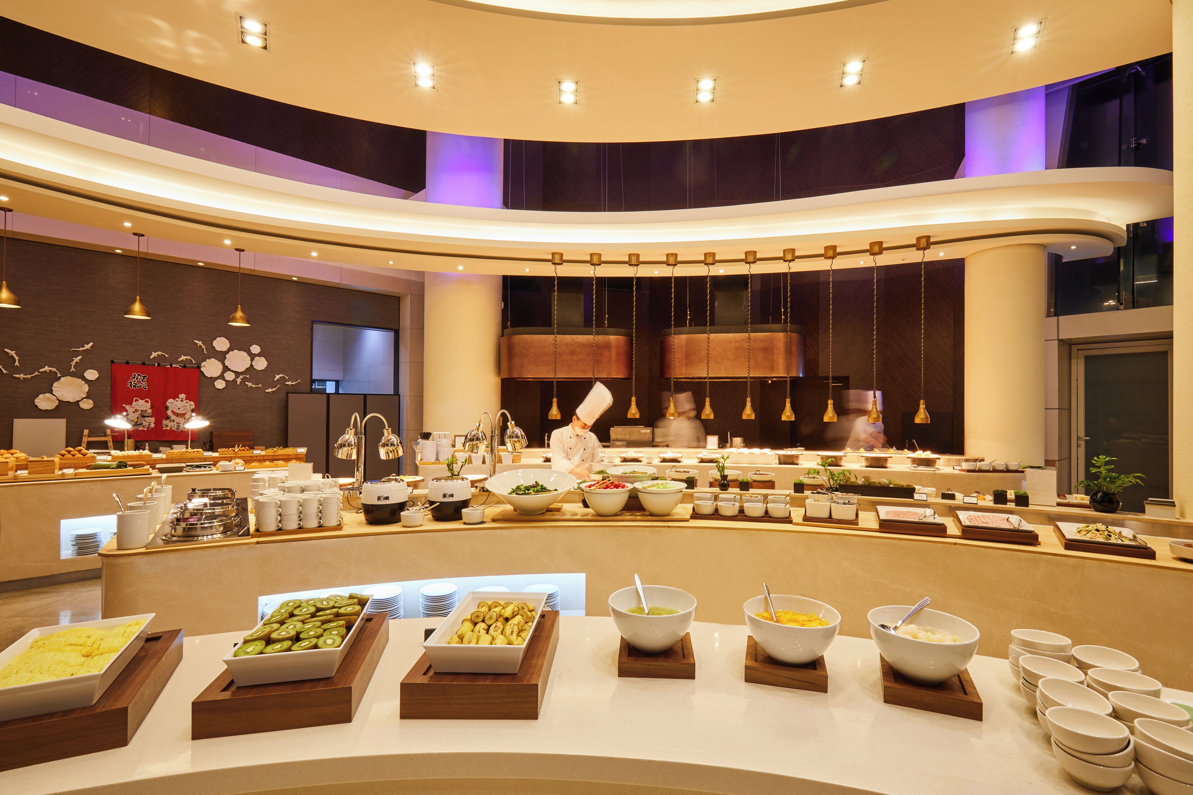 A buffet setup with various food items and a chef preparing food.