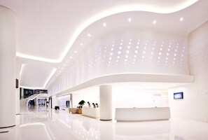 A modern, spacious lobby with a reception desk, seating area, and a staircase leading to upper floors. - Sono Calm Yeosu (Yeosu)