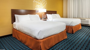 A hotel room with two beds, a nightstand, a lamp, and an air conditioning unit.