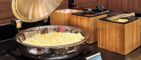 A buffet setup with scrambled eggs, a large bowl, and a sign indicating the dish.
